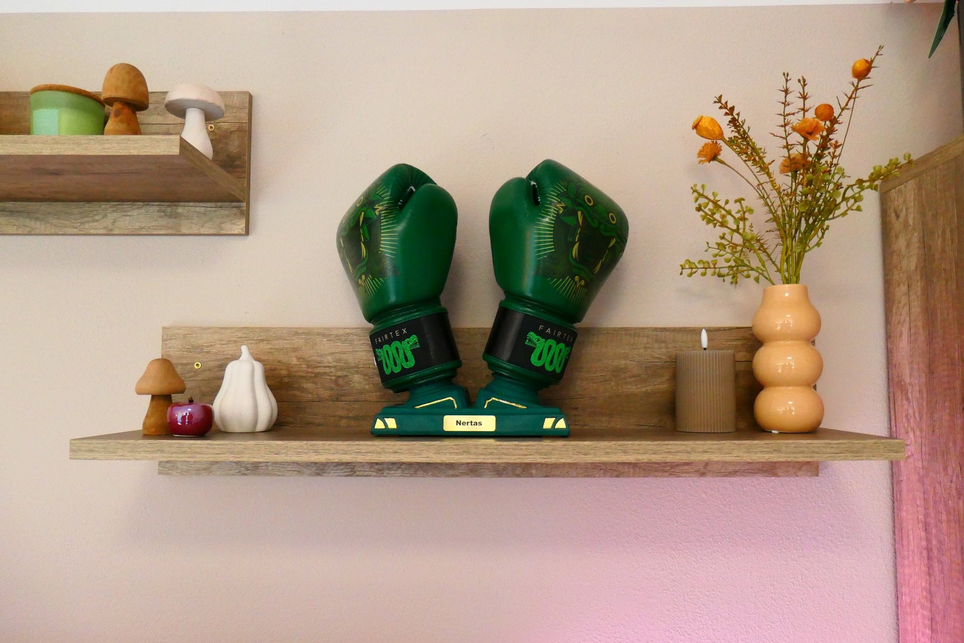 Limitierter Grüner Nertas Boxhandschuhhalter/ Boxhandschuhständer mit vergoldeten(24K) Details. Inklusive der Messing Personalisierung. Zu sehen mit Boxhandschuhen auf einem Regalbrett mit Deko.