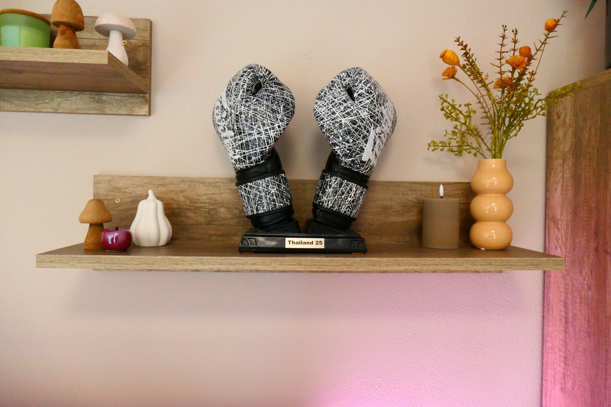 Schwarzer Nertas Boxhandschuhhalter/ Boxhandschuhständer mit der Edelstahl Personalisierung. Zu sehen mit Boxhandschuhen auf einem Regalbrett mit Deko.