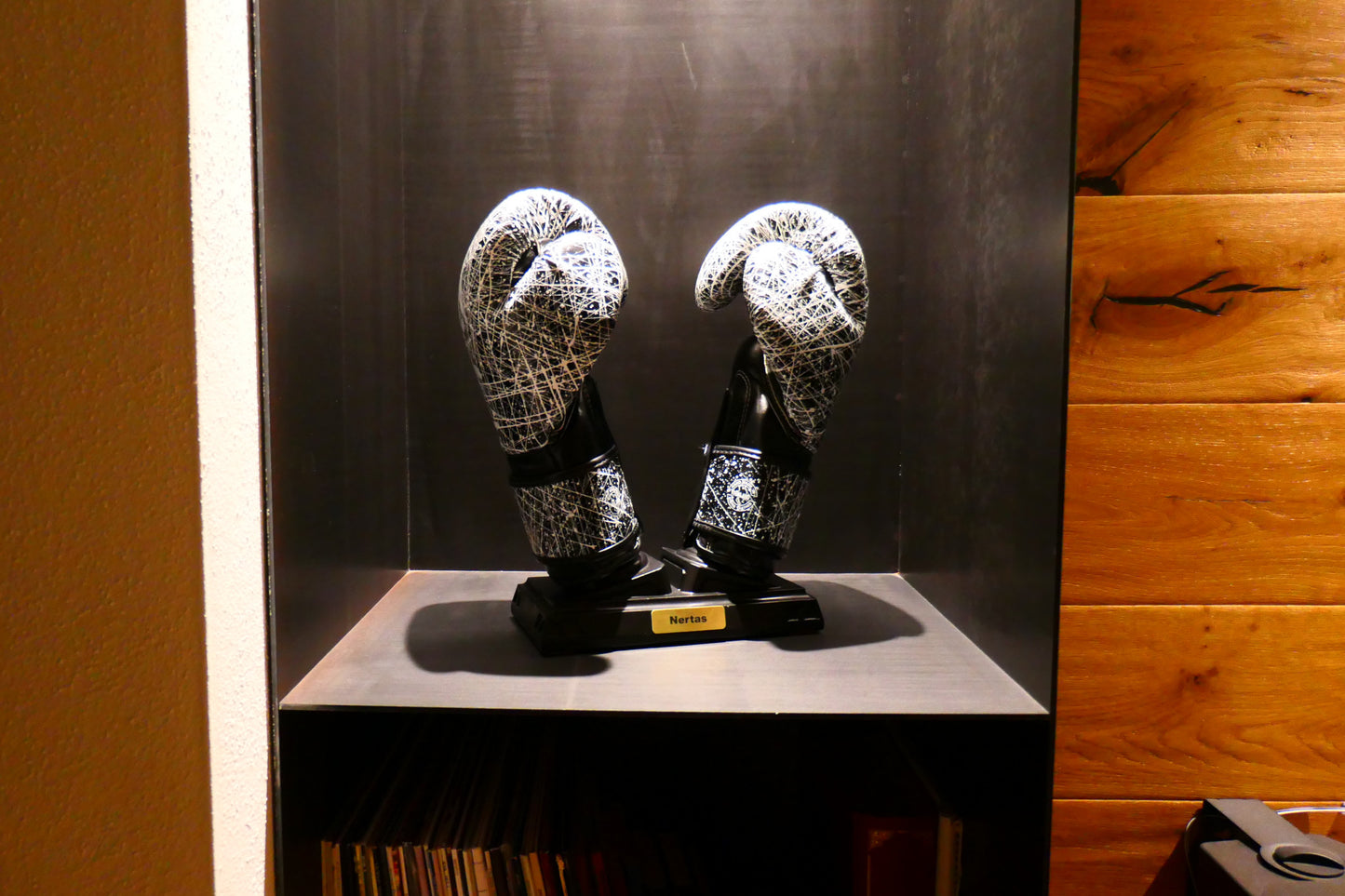 Schwarzer Nertas Boxhandschuhständer/-halter mit Boxhandschuhen. Platziert in einem Designer Stahl Regal. Beleuchtet von oben