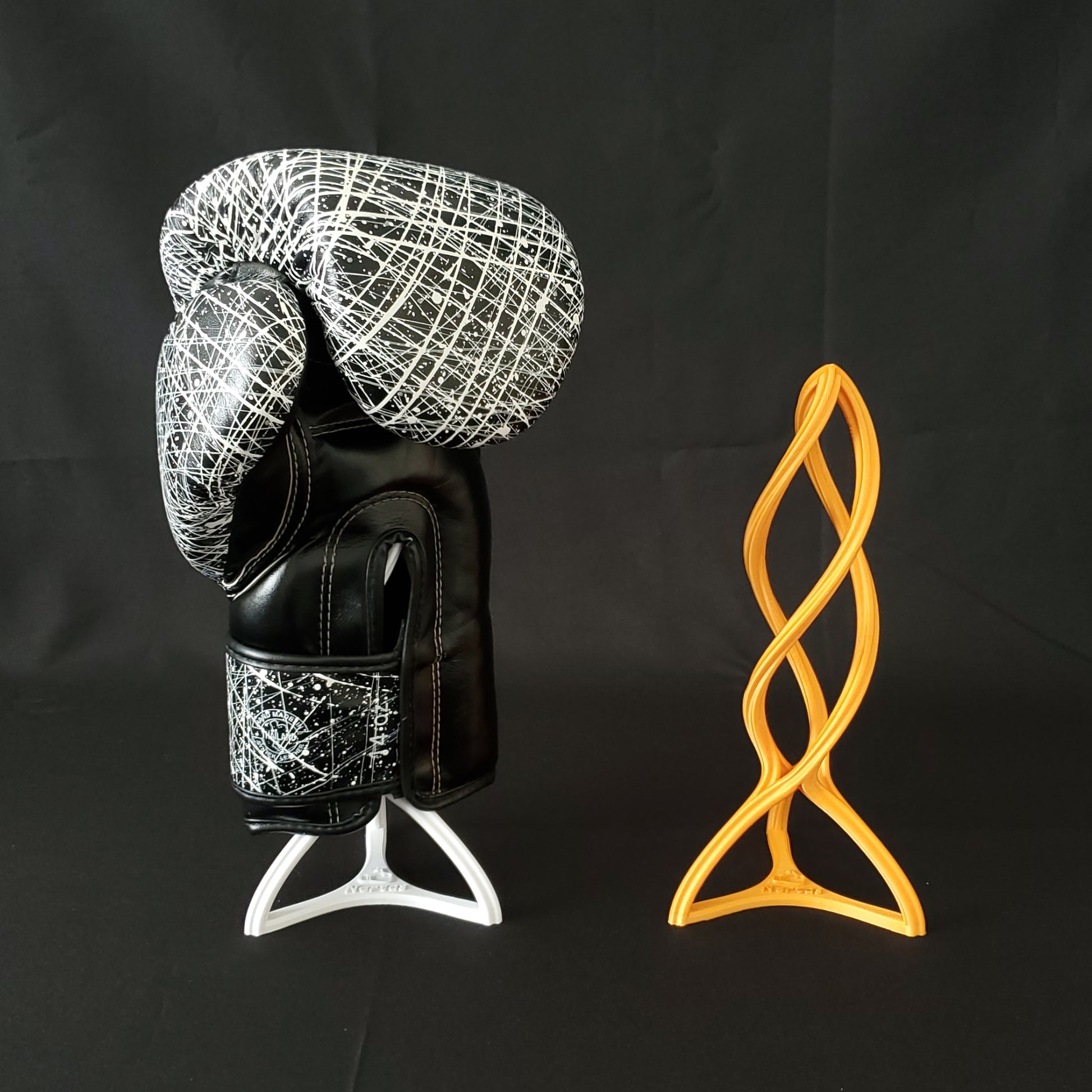 Das Bild zeigt zweimal den Nertas Boxhandschuh Trockner. Rechts in orange und links in weiß mit schwarz weißem Handschuh